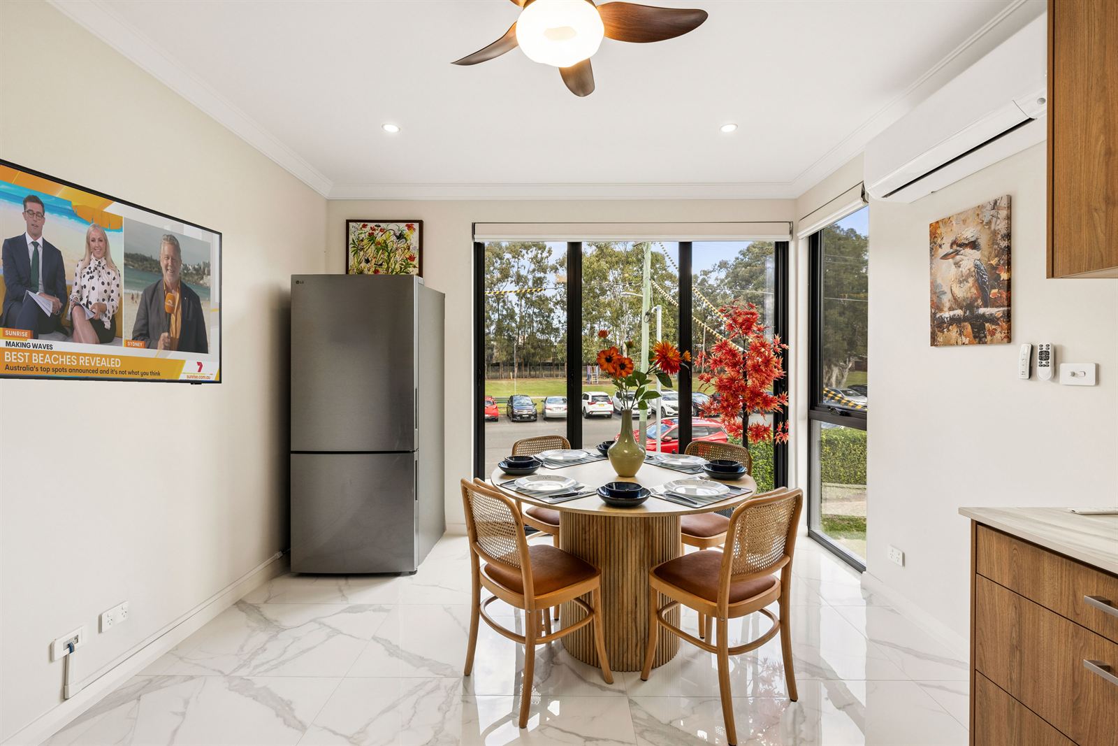 The dining table beside full-height windows looking onto the street's trees.