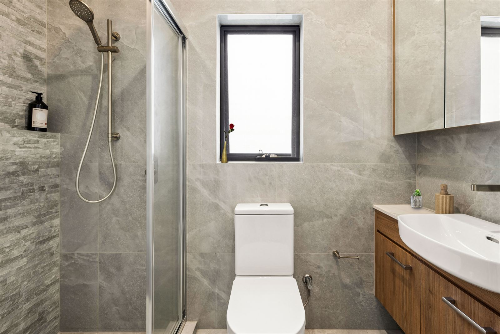 Bathroom with a glass shower, floating timber vanity and stone-look tiling.