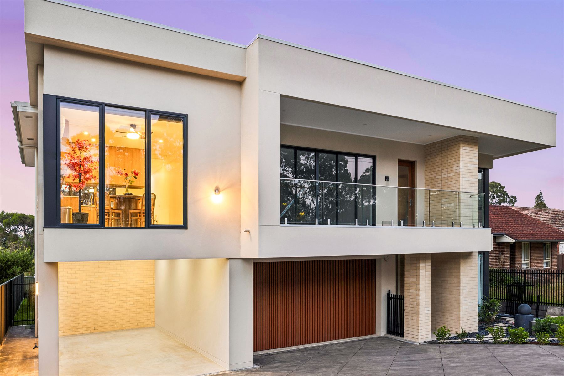The townhouse at dusk, balcony above the garage and warm light in the upstairs windows.