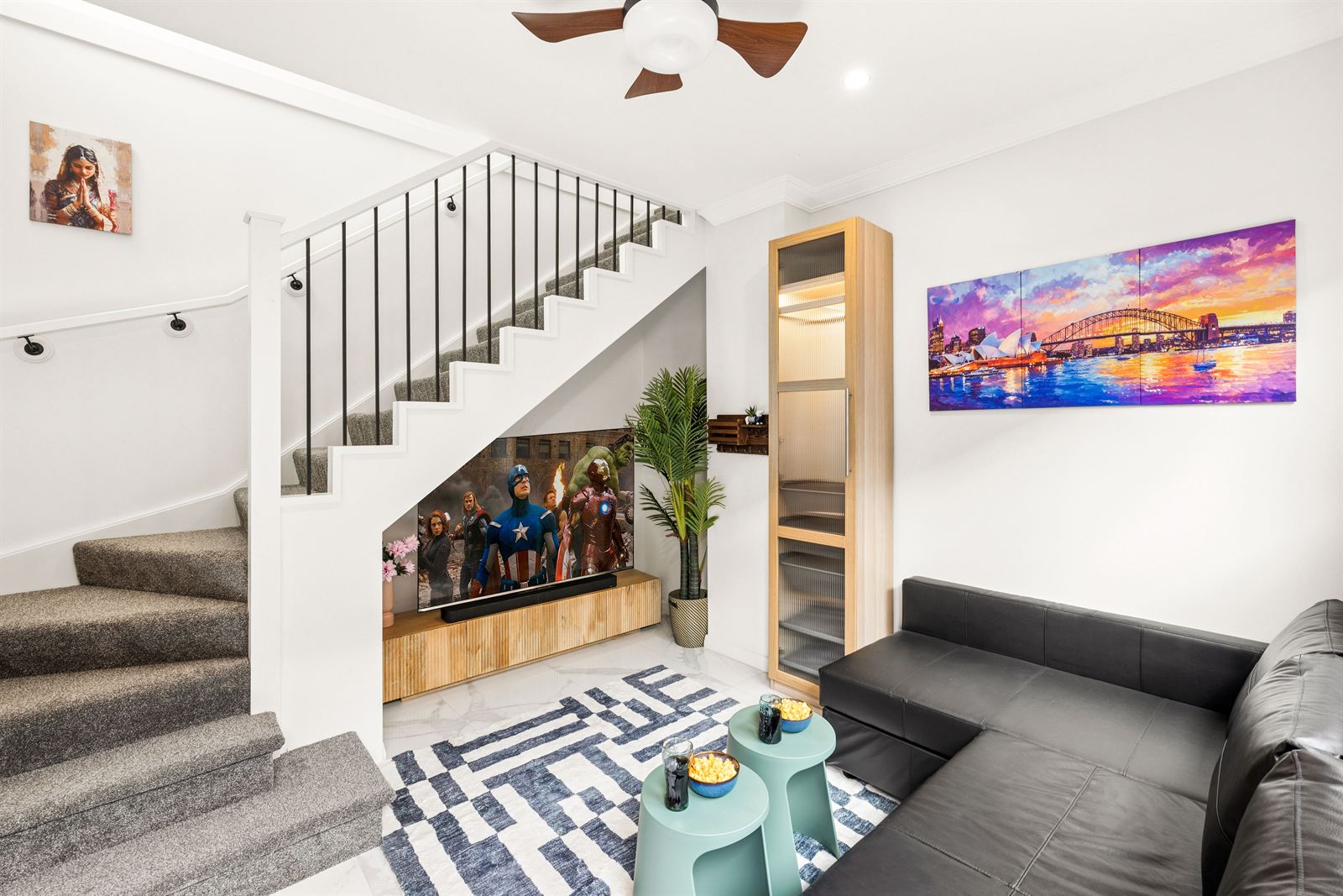 Living room with a leather sofa and the TV set into the wall beneath the staircase.